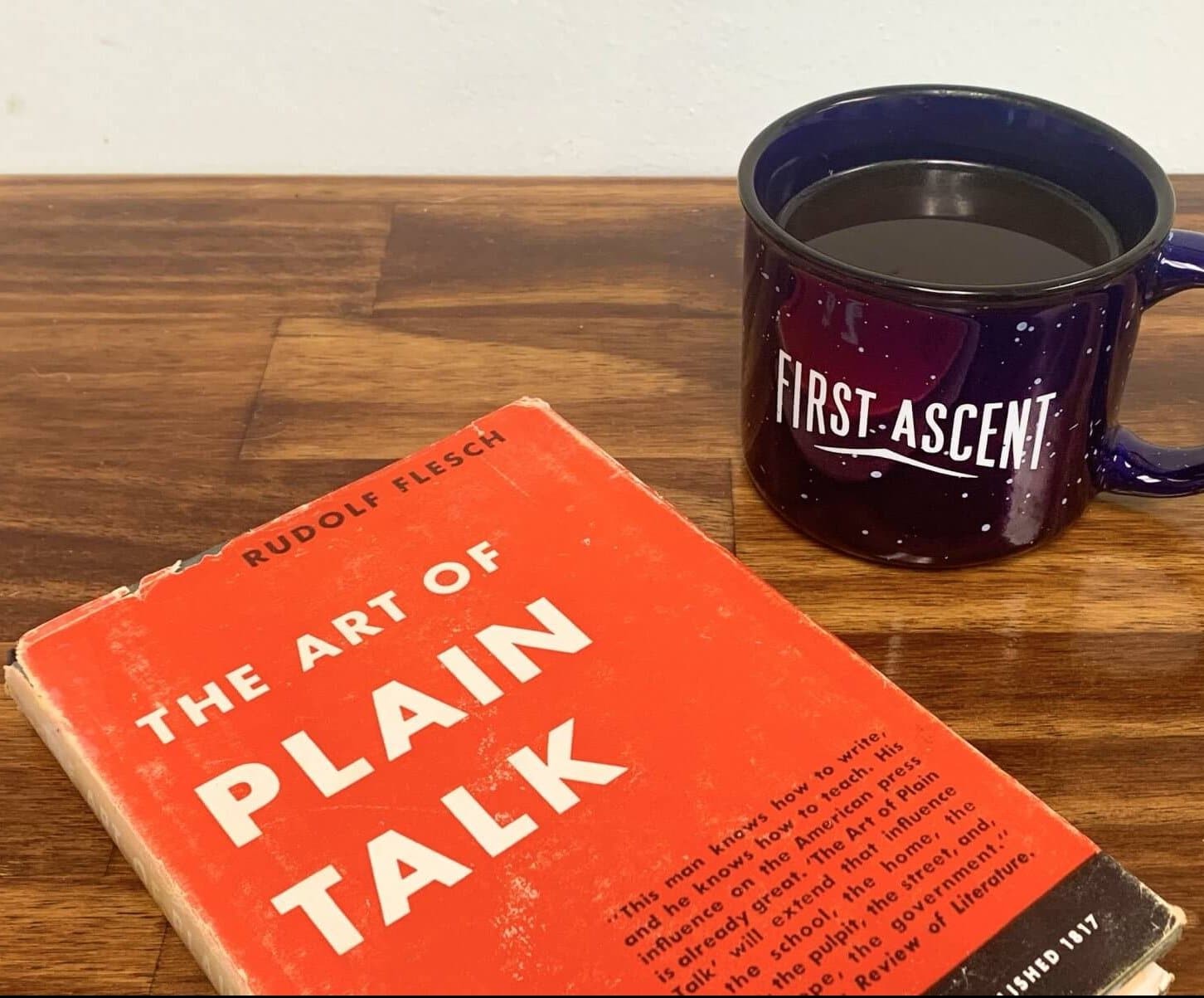 The book, The Art of Plain Talk, and a First Ascent coffee mug on a desk